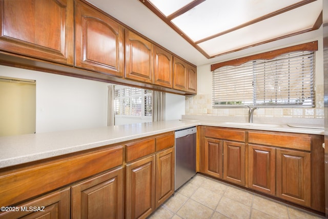 kitchen with light tile patterned flooring, sink, dishwasher, kitchen peninsula, and backsplash