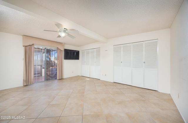 unfurnished bedroom with light tile patterned floors, ceiling fan, a textured ceiling, two closets, and beamed ceiling