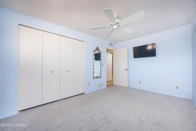 unfurnished bedroom with light colored carpet, ceiling fan, and a closet