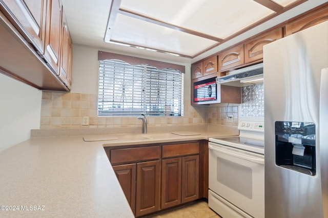 kitchen with stainless steel refrigerator with ice dispenser, sink, tasteful backsplash, and electric stove