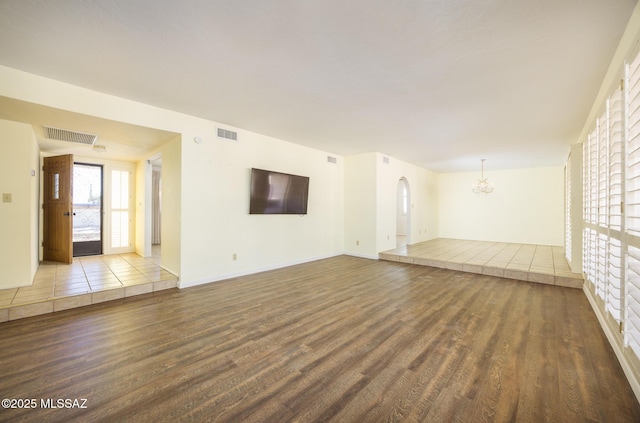 unfurnished living room with a chandelier and light wood-type flooring