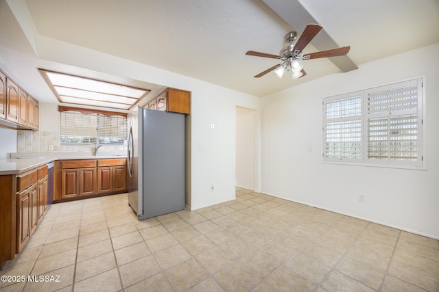 kitchen with light tile patterned flooring, stainless steel refrigerator, tasteful backsplash, sink, and ceiling fan