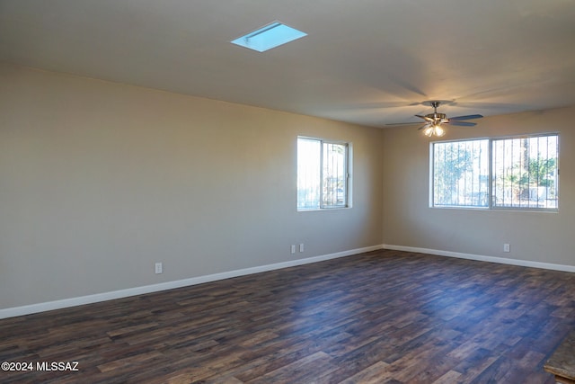 empty room featuring dark hardwood / wood-style flooring, a skylight, and ceiling fan