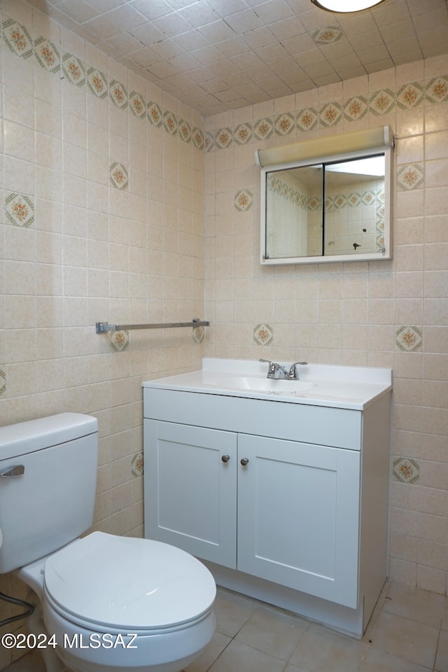 bathroom with tile walls, vanity, toilet, and tile patterned flooring