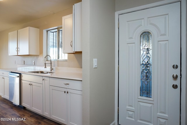 kitchen with dark wood-type flooring, stainless steel dishwasher, sink, and white cabinets