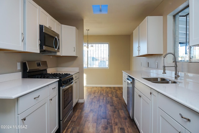 kitchen featuring sink, appliances with stainless steel finishes, decorative light fixtures, white cabinets, and dark wood-type flooring