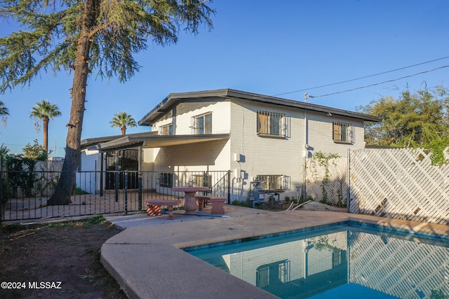 back of property featuring a fenced in pool and a patio area