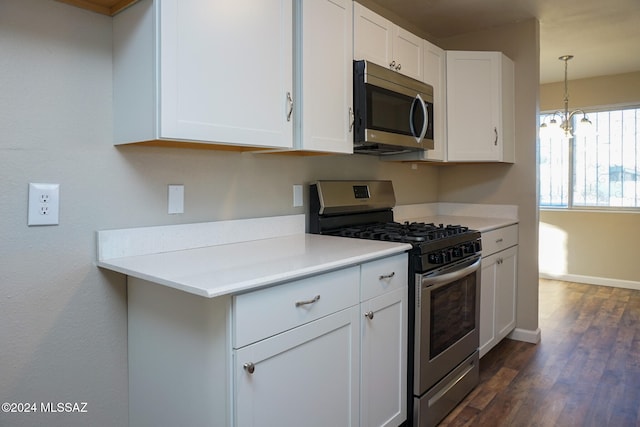 kitchen featuring white cabinetry, appliances with stainless steel finishes, decorative light fixtures, an inviting chandelier, and dark wood-type flooring