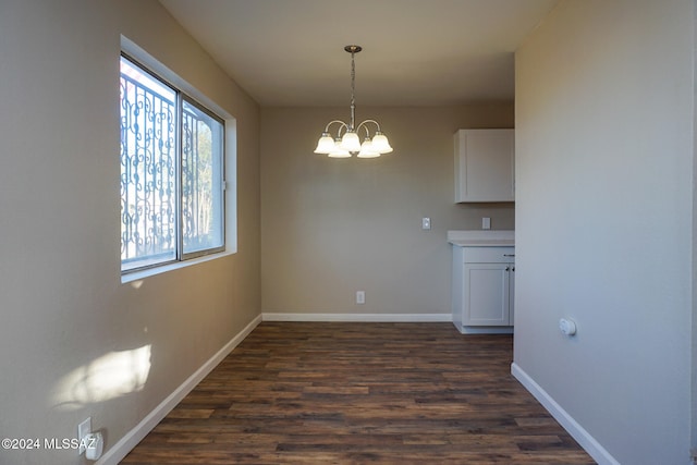 unfurnished dining area featuring dark hardwood / wood-style flooring and a notable chandelier