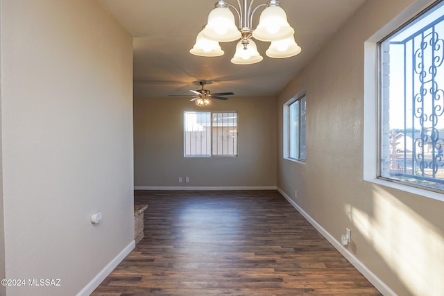 empty room with dark wood-type flooring and ceiling fan with notable chandelier