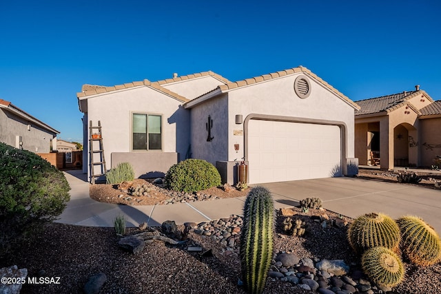mediterranean / spanish home featuring a garage, concrete driveway, a tiled roof, and stucco siding
