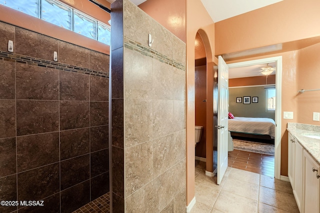 full bath featuring toilet, a tile shower, ensuite bathroom, a ceiling fan, and vanity