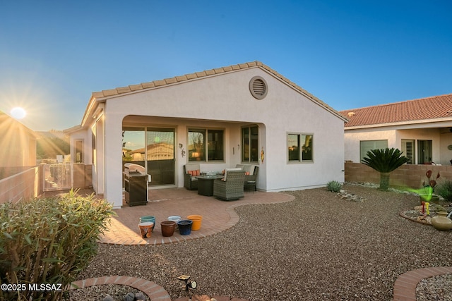 rear view of property featuring a tile roof, a patio, a fenced backyard, and stucco siding