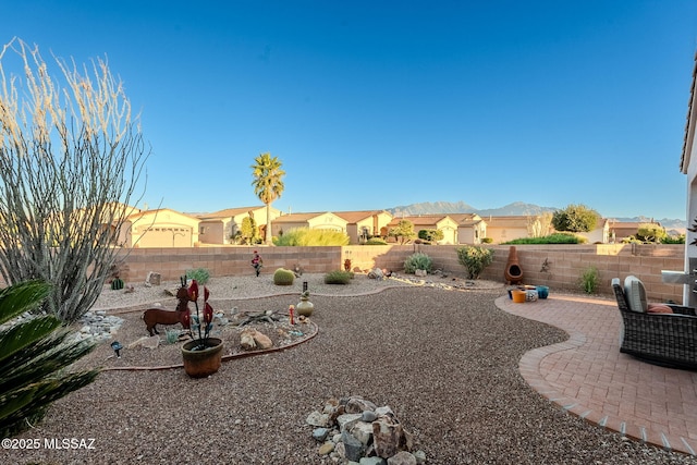 view of yard with a patio area, a fenced backyard, and a mountain view