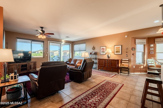 living area with light tile patterned floors, a ceiling fan, and plenty of natural light
