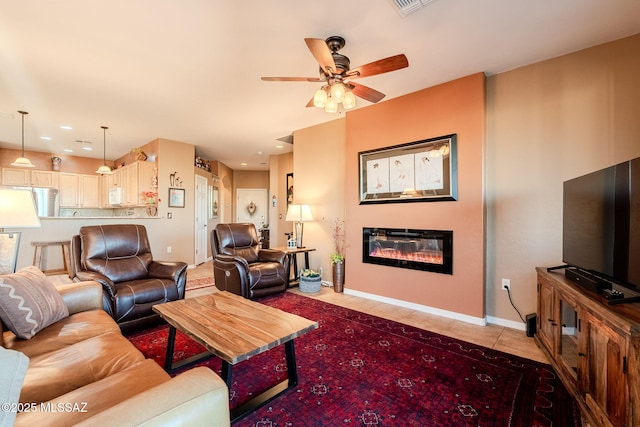 living room with a ceiling fan, a glass covered fireplace, light tile patterned floors, baseboards, and recessed lighting
