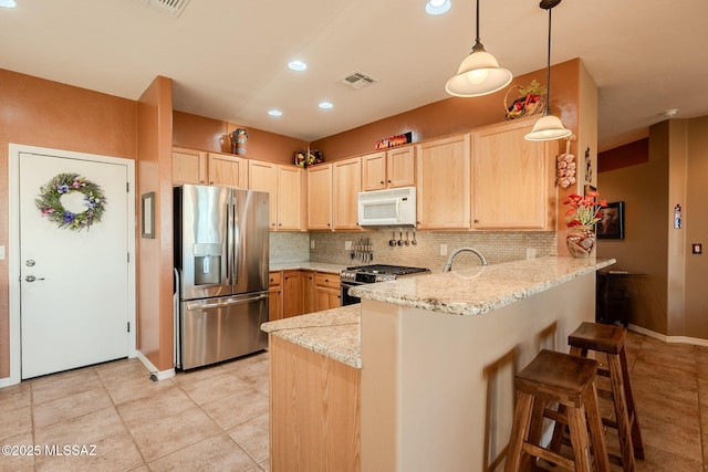 kitchen featuring light brown cabinets, backsplash, a peninsula, appliances with stainless steel finishes, and visible vents