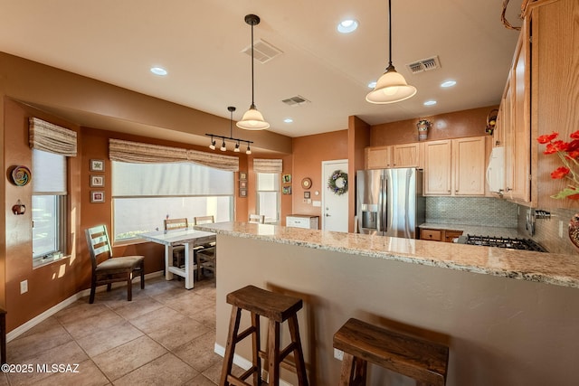 kitchen featuring a peninsula, visible vents, stainless steel fridge, and white microwave