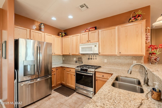 kitchen with light brown cabinetry, stainless steel appliances, visible vents, and a sink