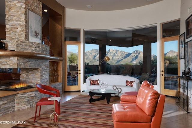 living room with a mountain view, light tile patterned flooring, and a stone fireplace