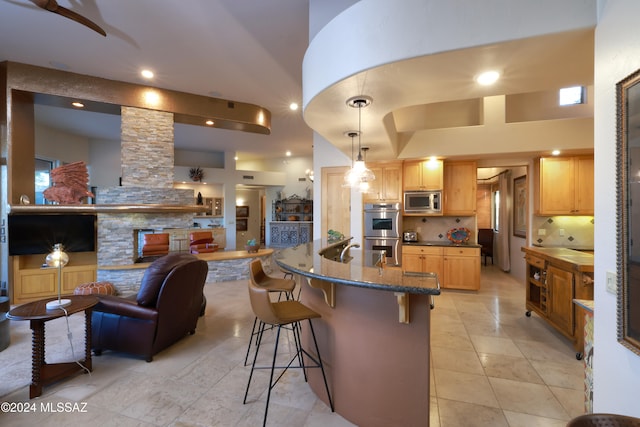 kitchen with a breakfast bar area, decorative columns, a towering ceiling, appliances with stainless steel finishes, and decorative backsplash