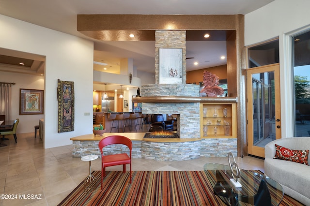 living room with a stone fireplace and light tile patterned floors