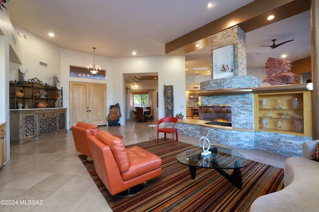 tiled living room with a fireplace and ceiling fan with notable chandelier