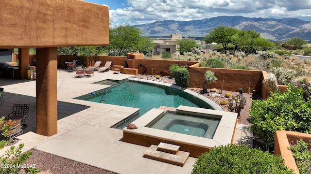 pool featuring a patio area, an in ground hot tub, and a mountain view