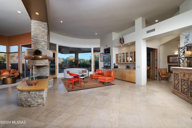 tiled living room featuring ornate columns, a towering ceiling, and french doors