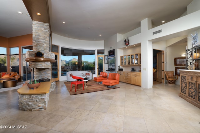 living area featuring a wealth of natural light, visible vents, decorative columns, and a high ceiling