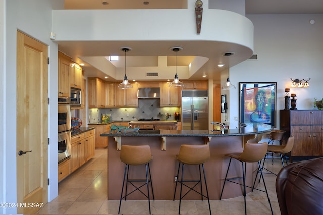 kitchen with a kitchen bar, built in appliances, light tile patterned floors, exhaust hood, and decorative light fixtures