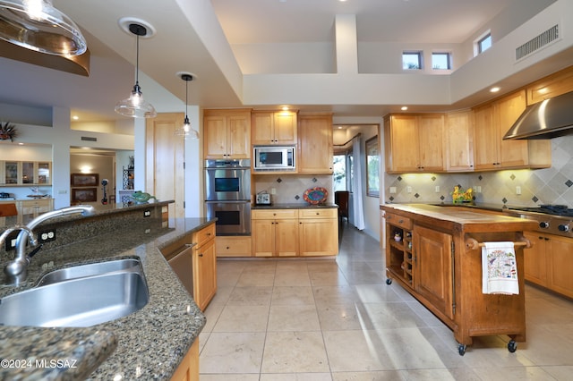 kitchen with butcher block counters, a center island, decorative backsplash, sink, and appliances with stainless steel finishes