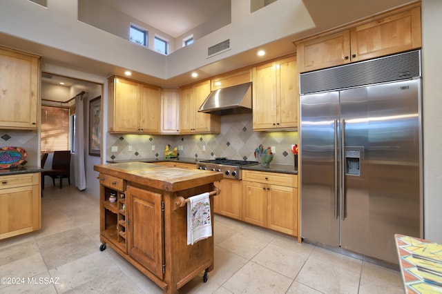 kitchen featuring light brown cabinetry, wood counters, appliances with stainless steel finishes, and exhaust hood