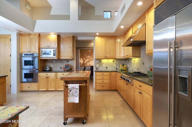 kitchen with butcher block counters, built in appliances, exhaust hood, light tile patterned flooring, and backsplash