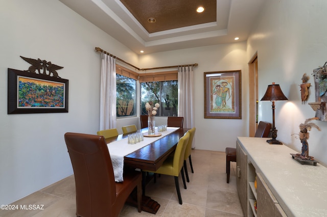 dining room with a tray ceiling, light tile patterned flooring, and recessed lighting