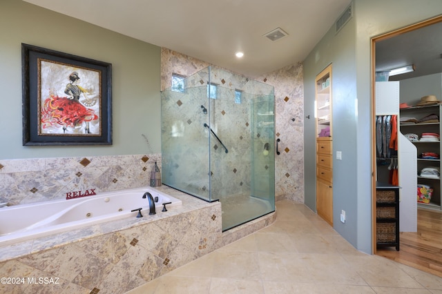 full bathroom featuring a shower stall, a walk in closet, visible vents, and a whirlpool tub