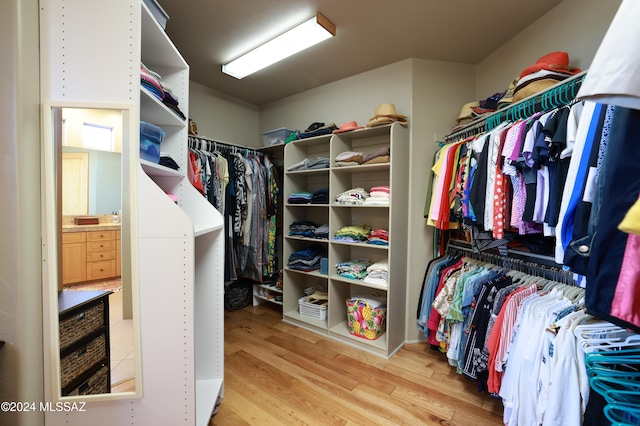 walk in closet with light hardwood / wood-style floors