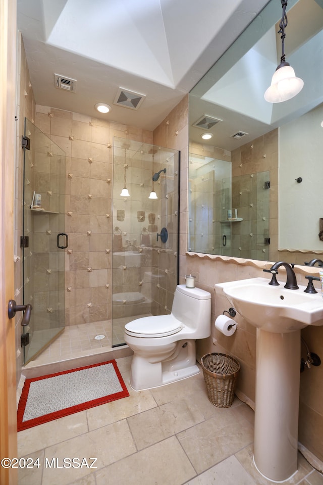 bathroom with tile walls, toilet, and a shower with door