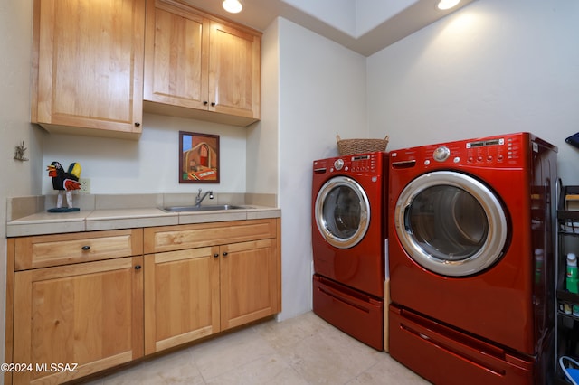 washroom with a sink, light tile patterned flooring, cabinet space, and washer and dryer