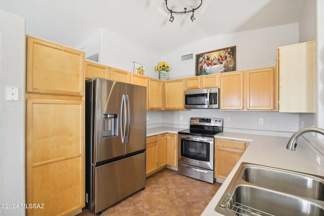 kitchen featuring sink, vaulted ceiling, light brown cabinetry, appliances with stainless steel finishes, and light tile patterned flooring