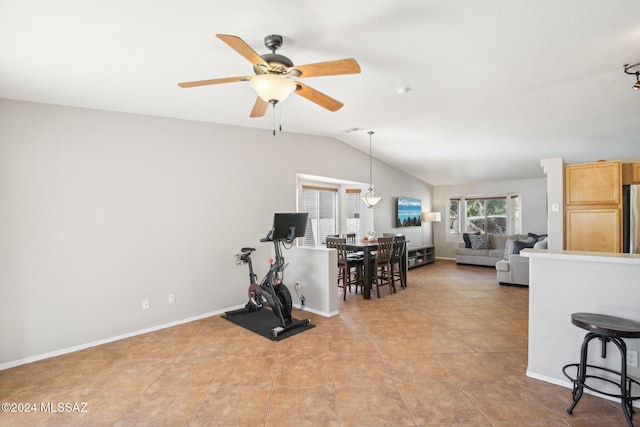 exercise room with ceiling fan, light tile patterned floors, and vaulted ceiling