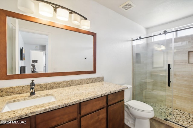 bathroom with vanity, toilet, and a shower with shower door