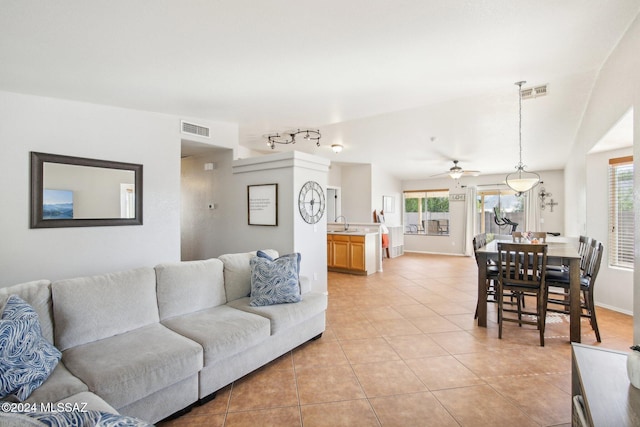 tiled living room featuring ceiling fan, sink, a wealth of natural light, and vaulted ceiling