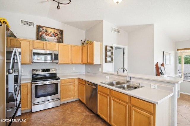 kitchen with kitchen peninsula, sink, vaulted ceiling, and appliances with stainless steel finishes