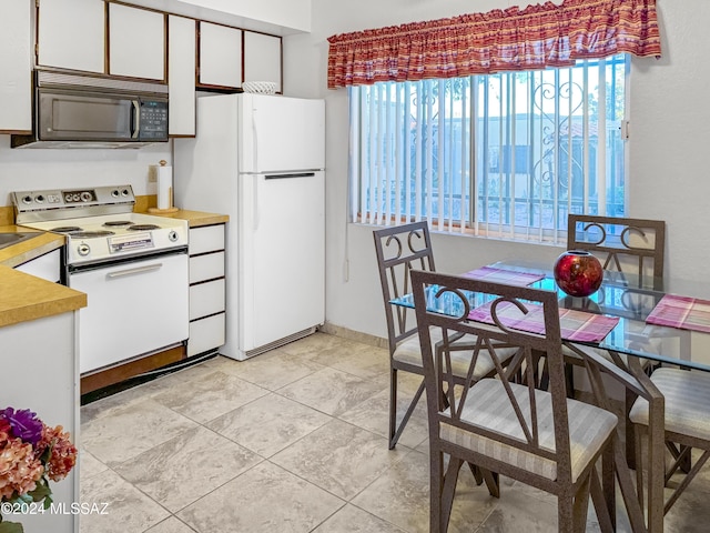 kitchen with plenty of natural light, white cabinetry, light tile patterned flooring, and white appliances