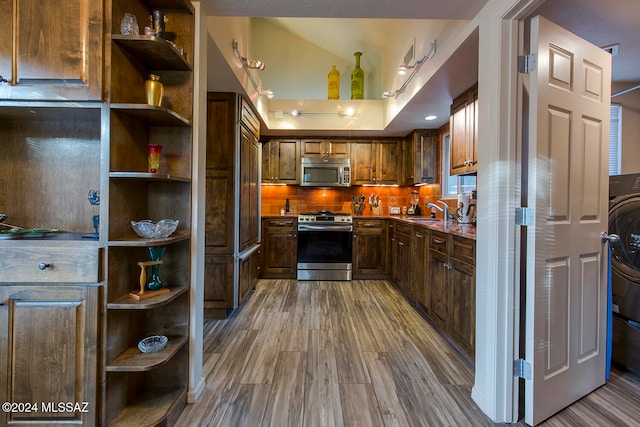 kitchen with hardwood / wood-style floors, lofted ceiling, backsplash, sink, and appliances with stainless steel finishes