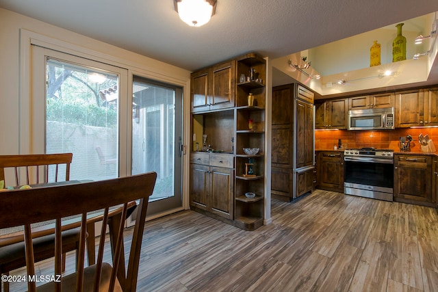 kitchen with a textured ceiling, decorative backsplash, stainless steel appliances, and dark hardwood / wood-style floors