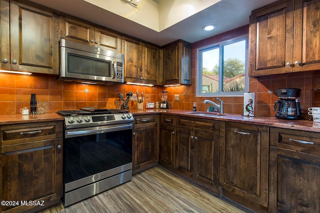 kitchen featuring decorative backsplash, sink, stainless steel appliances, and light hardwood / wood-style flooring