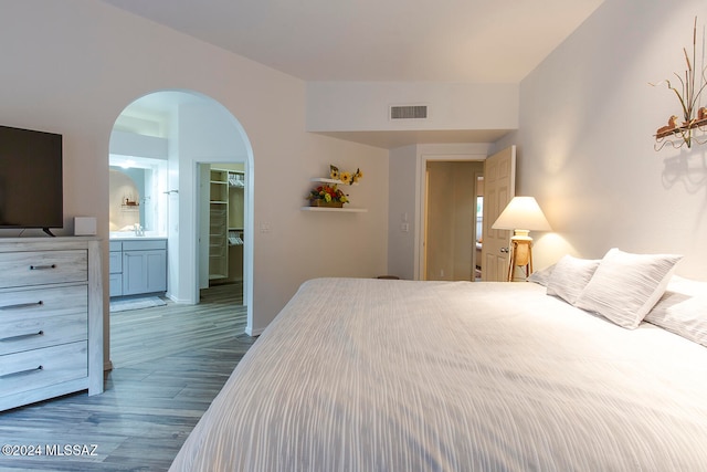 bedroom with a walk in closet, dark hardwood / wood-style flooring, sink, connected bathroom, and a closet