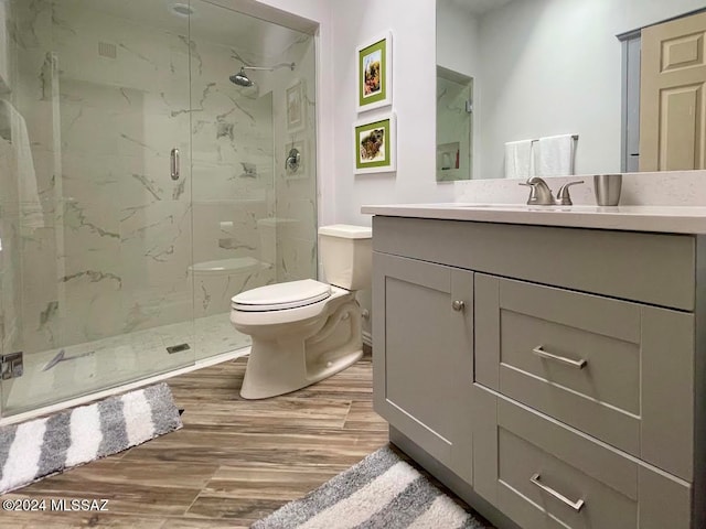 bathroom featuring vanity, toilet, wood-type flooring, and a shower with door